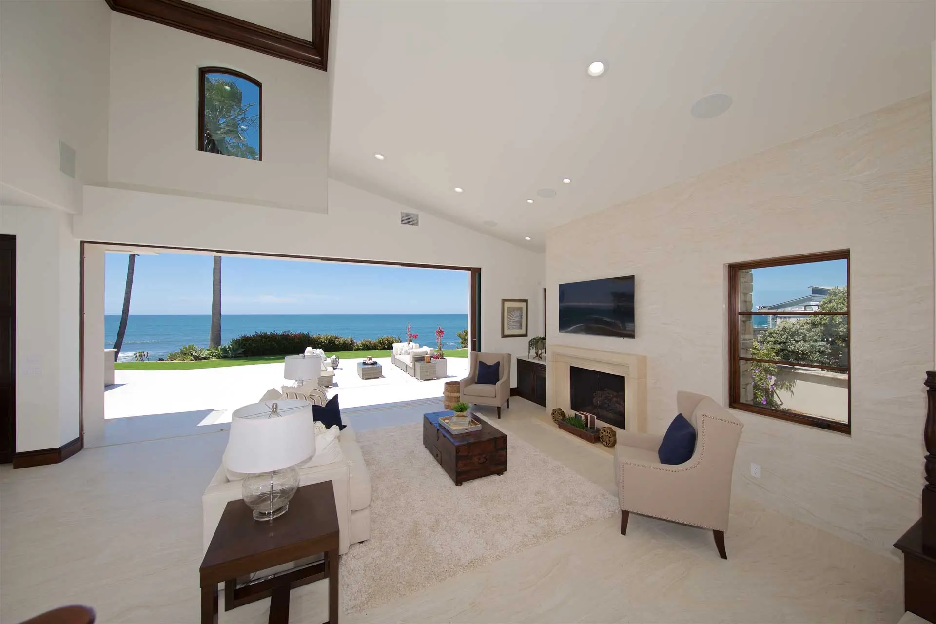 Renovated great room with vaulted ceiling and a wall of glass opening to a patio