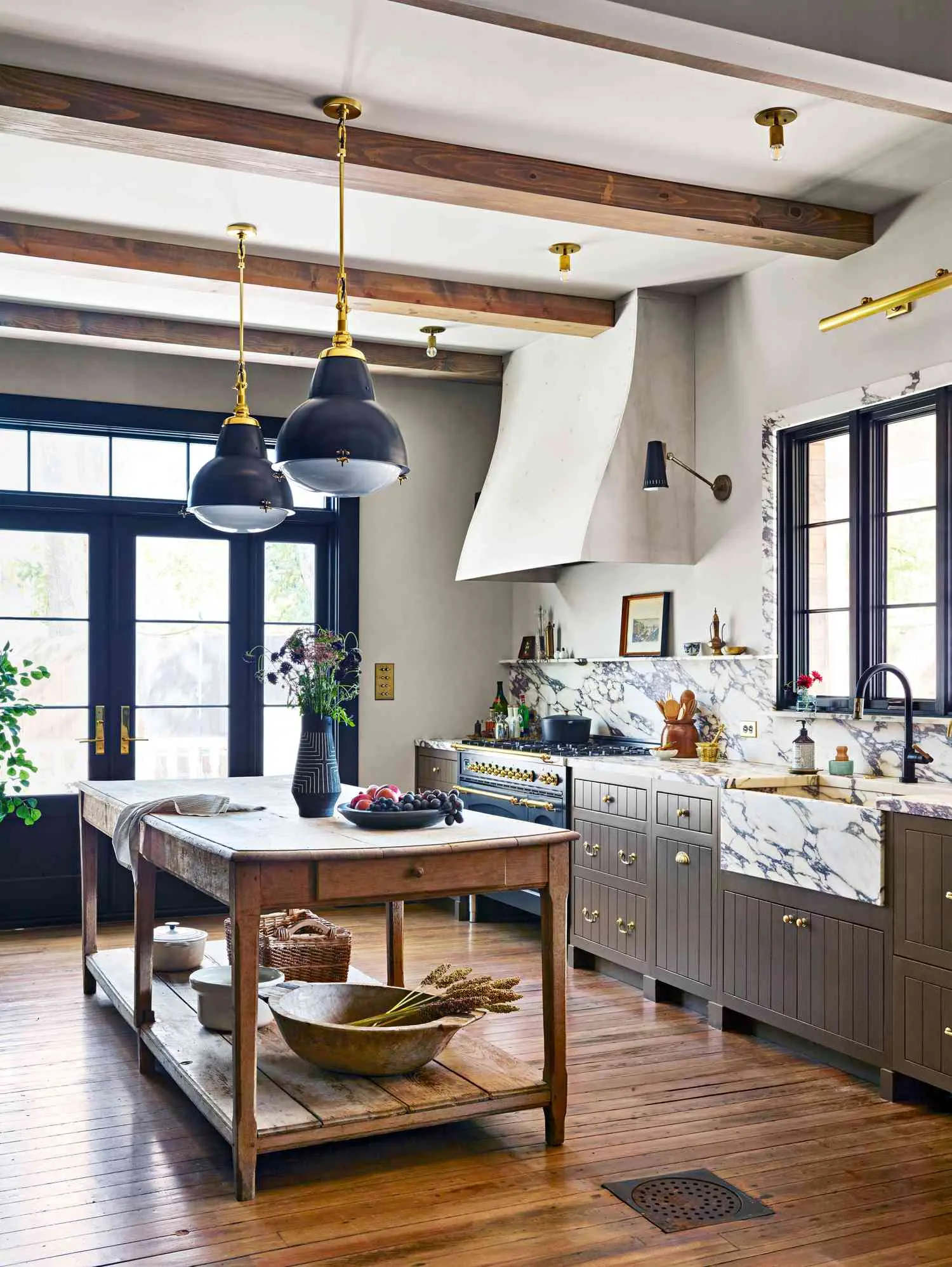 Remodeled kitchen with exposed wood beams, marble counters, and a custom plaster range hood